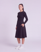 A woman modeling a lightweight athletic black flared skirt and side pockets, paired with white socks and white sneakers