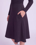 A woman close up modeling a lightweight athletic black flared skirt with side pockets