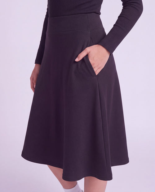 A woman close up modeling a lightweight athletic black flared skirt with side pockets