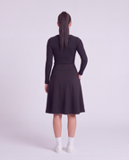 A woman back modeling a lightweight athletic black flared skirt with side pockets, paired with white socks and white sneakers