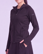 A woman wearing a black zip-up hoodie with a hood, side pockets, and a small 'mint' logo on the upper left sleeve